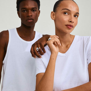 Two people wearing white tank tops against a plain background