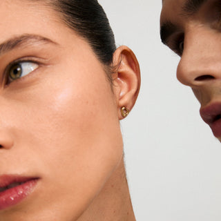 Close-up of a woman's ear with an earring against a neutral background