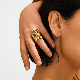 Gold ring on a finger with a neutral background