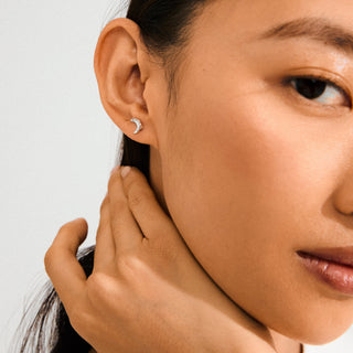 Close-up of a woman wearing a silver earring with a clear gemstone.