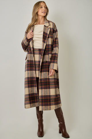 Women modelling a long plaid coat against a neutral photo back drop. 