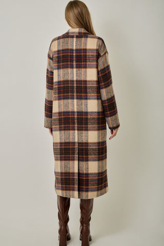 Women modelling a long plaid coat against a neutral photo back drop. 