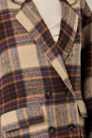 Women modelling a long plaid coat against a neutral photo back drop. 