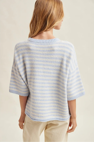 Woman wearing a light blue and white striped sweater on a beige background