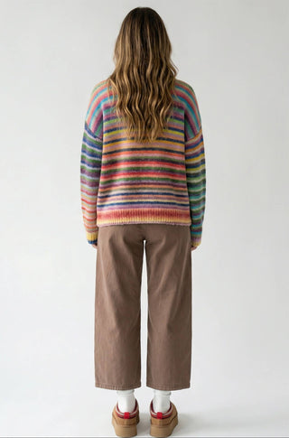 Person wearing a colorful striped sweater and brown pants on a white background