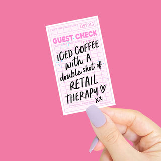 a sticker with the phrase iced coffee with a double shot of retail therapy in the shape of a ticker