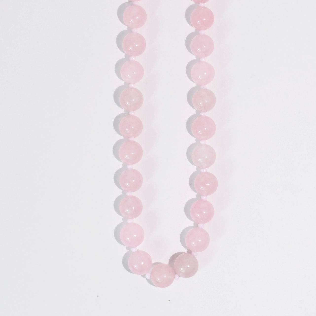A pink beaded necklace on a white background.