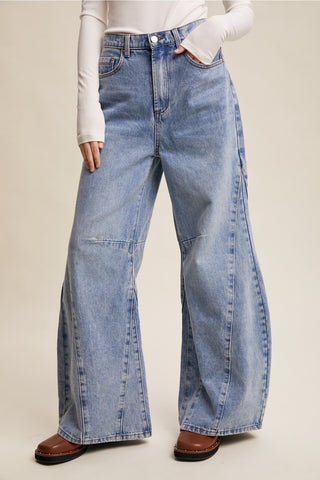 Person wearing blue wide-leg jeans on a plain background