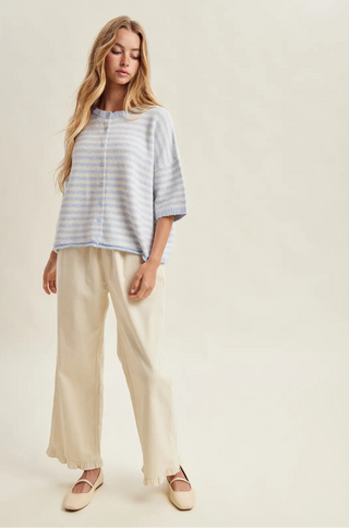 Woman wearing a striped shirt and beige pants on a plain background