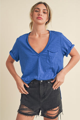 Woman wearing a blue top and black shorts against a beige background