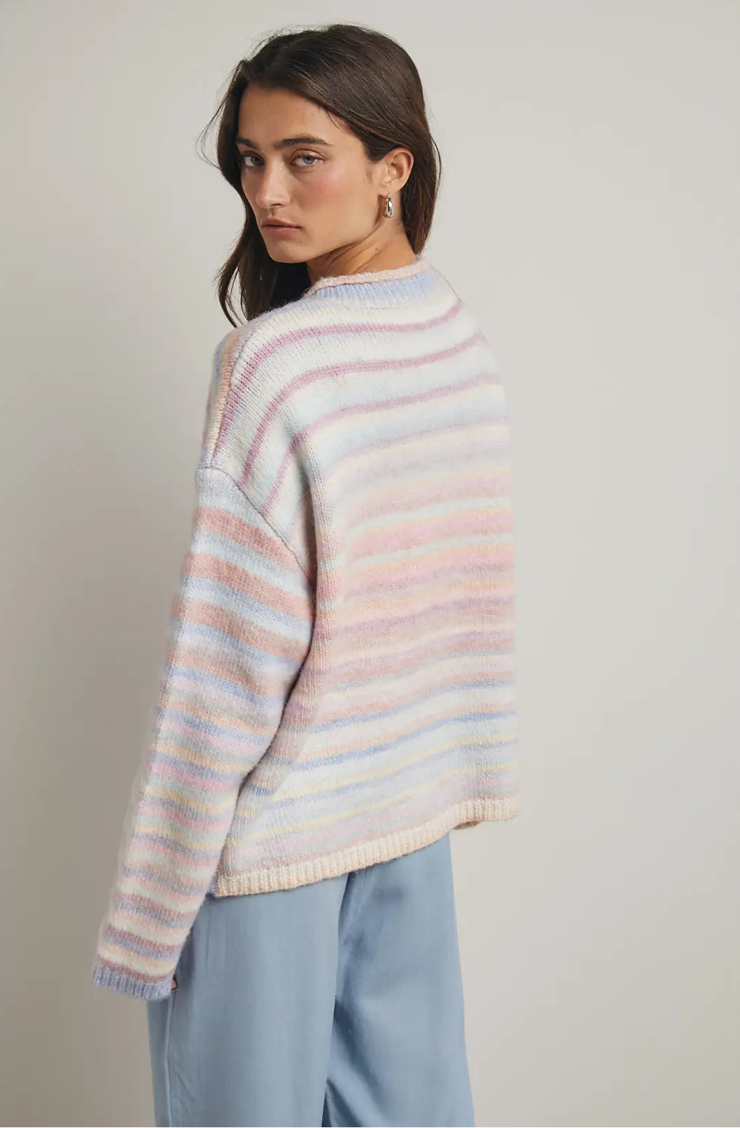 Women wearing a pastel cardigan on a plain background. 