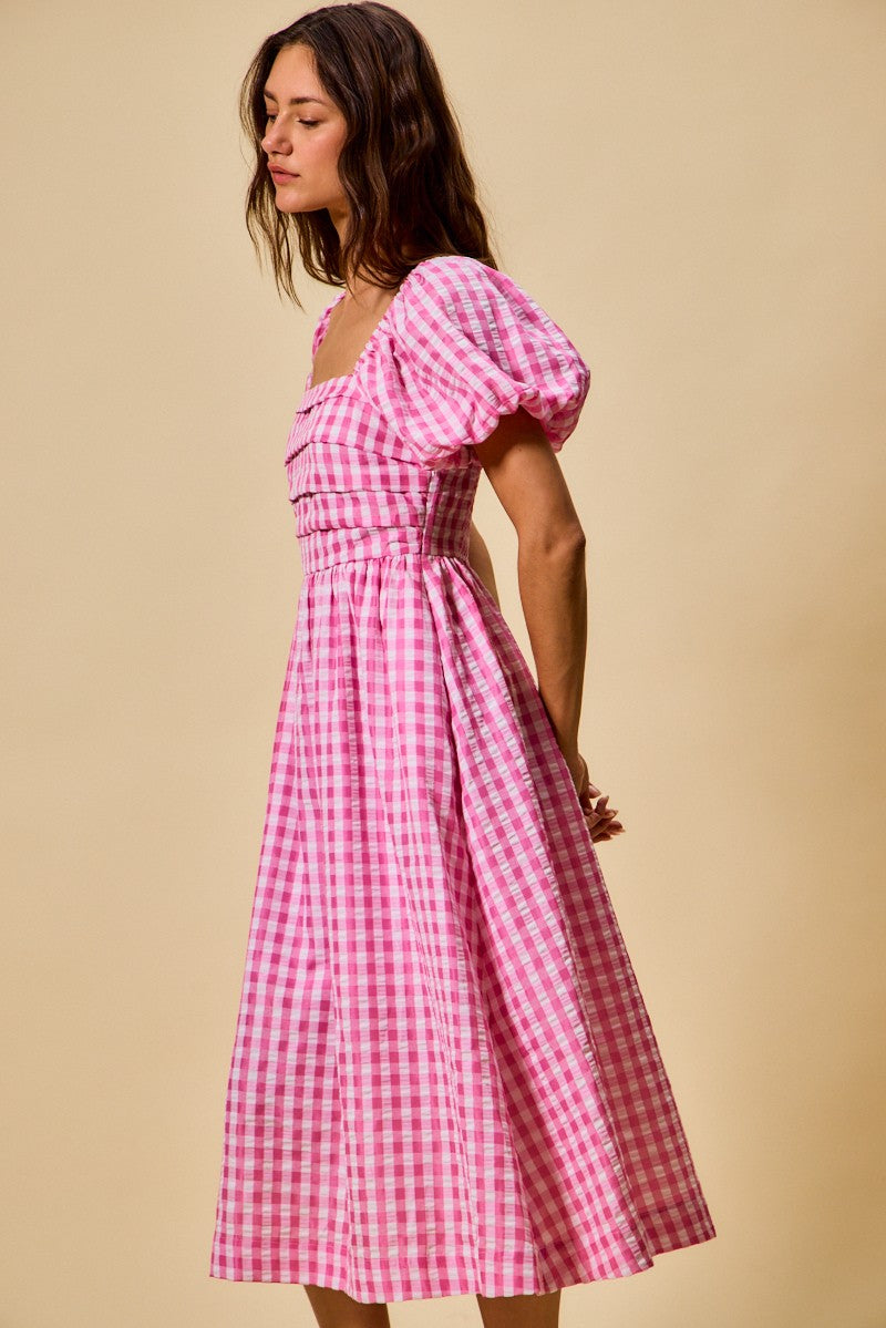 Woman wearing a pink checkered dress against a beige background