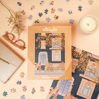 Villáger puzzle box with puzzle pieces and a candle on a pink surface
