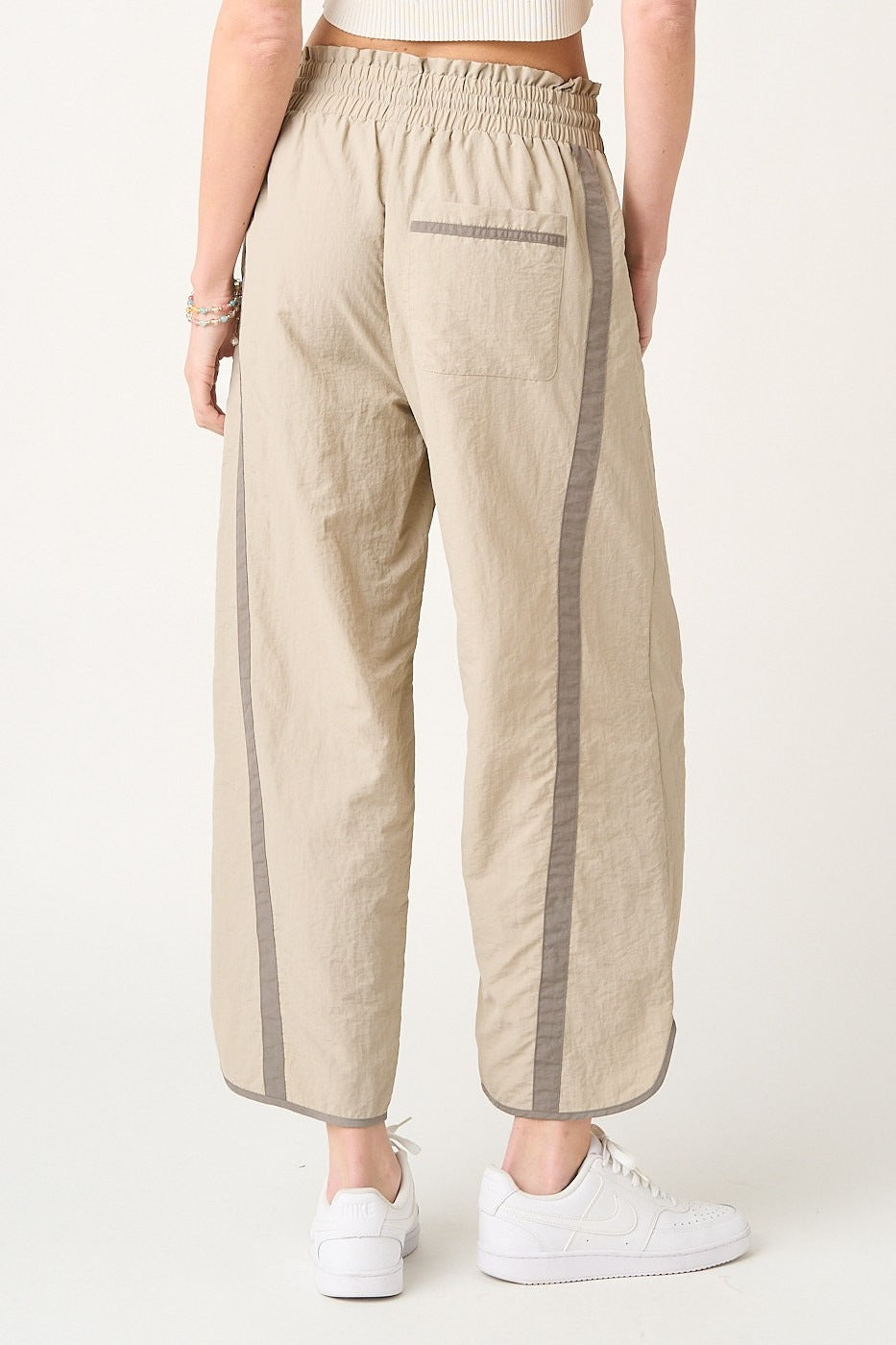 Beige pants with gray stripes worn by a person on a white background