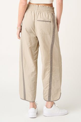 Beige pants with gray stripes worn by a person on a white background