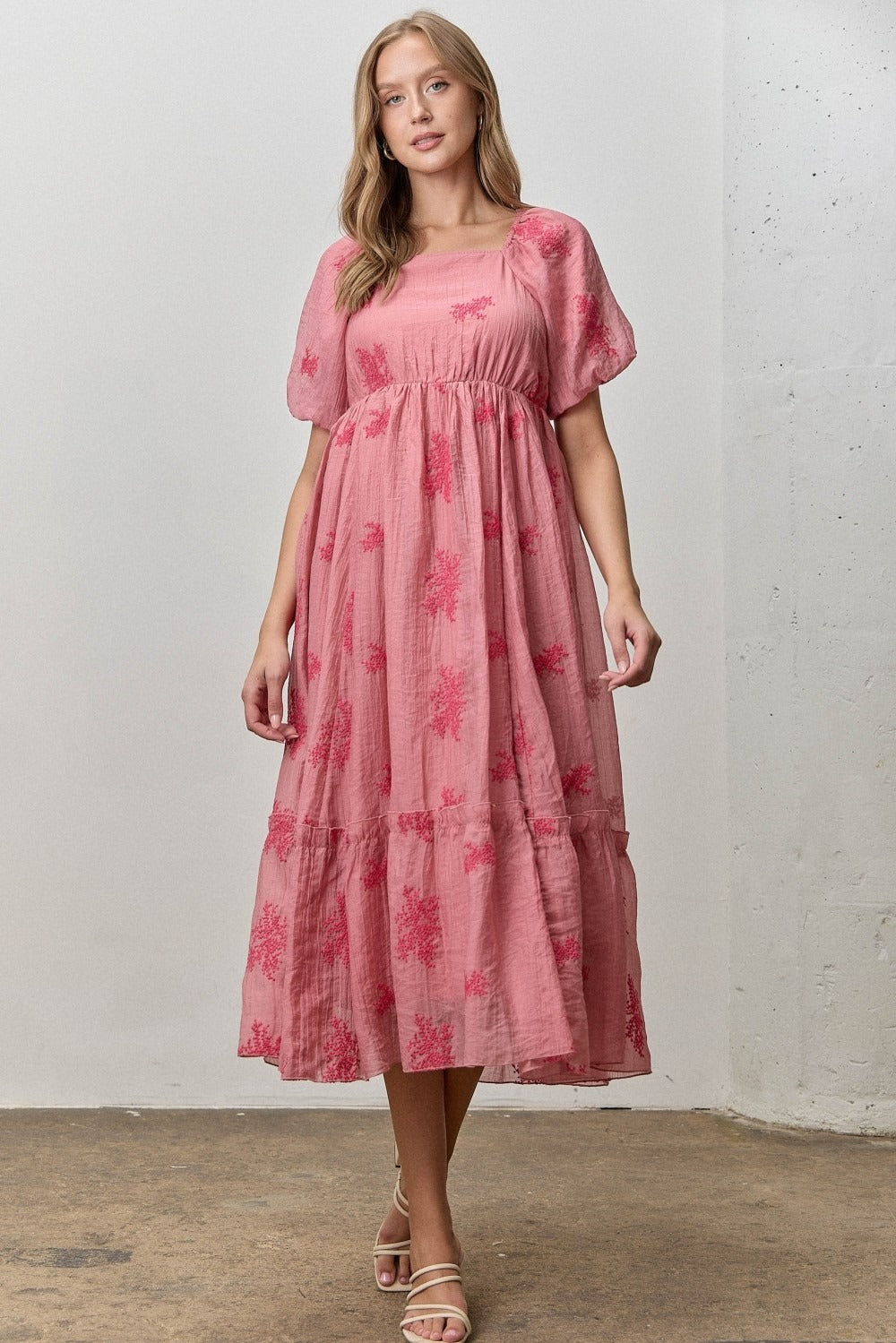 Woman wearing a pink floral dress against a plain background