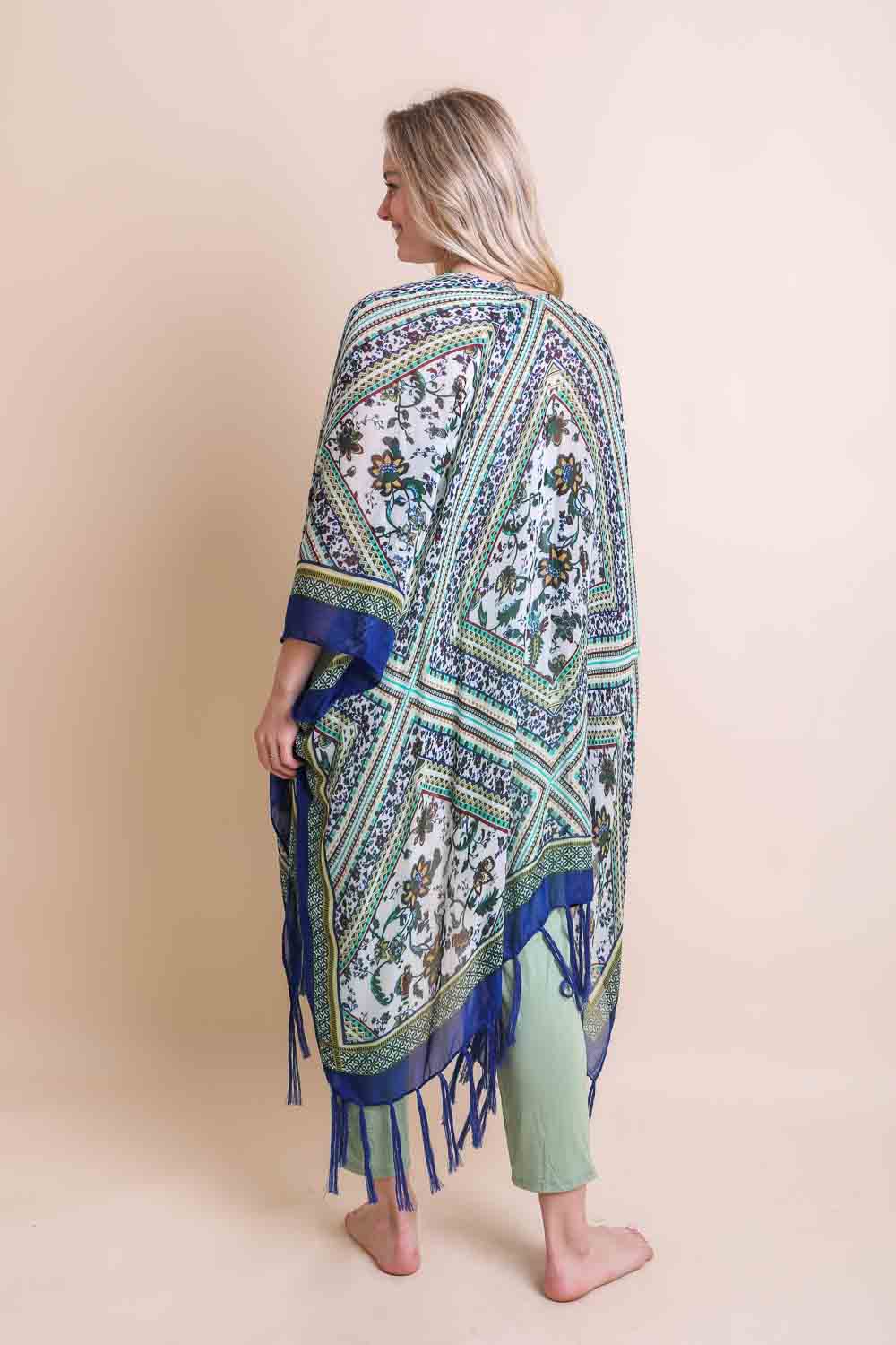 Woman wearing a patterned shawl with fringes on a beige background