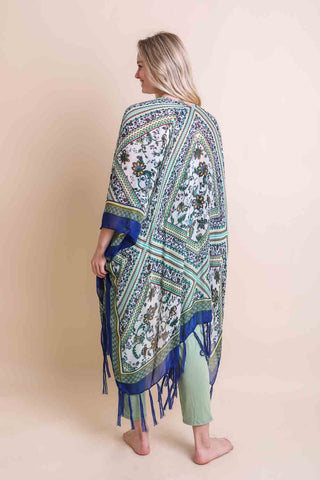 Woman wearing a patterned shawl with fringes on a beige background