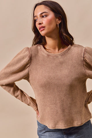 Woman wearing a beige textured sweater against a beige background