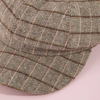 Close-up of a green checkered cap on a pink background