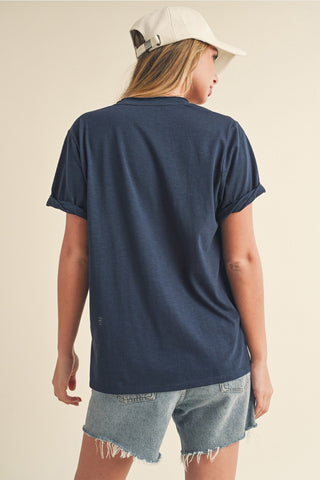 Person wearing a navy blue t-shirt and denim shorts on a beige background