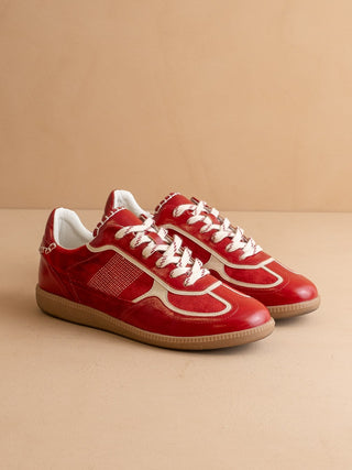 Red sneakers with white laces on a beige background