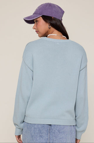 Person wearing a light blue sweater and purple cap on a beige background