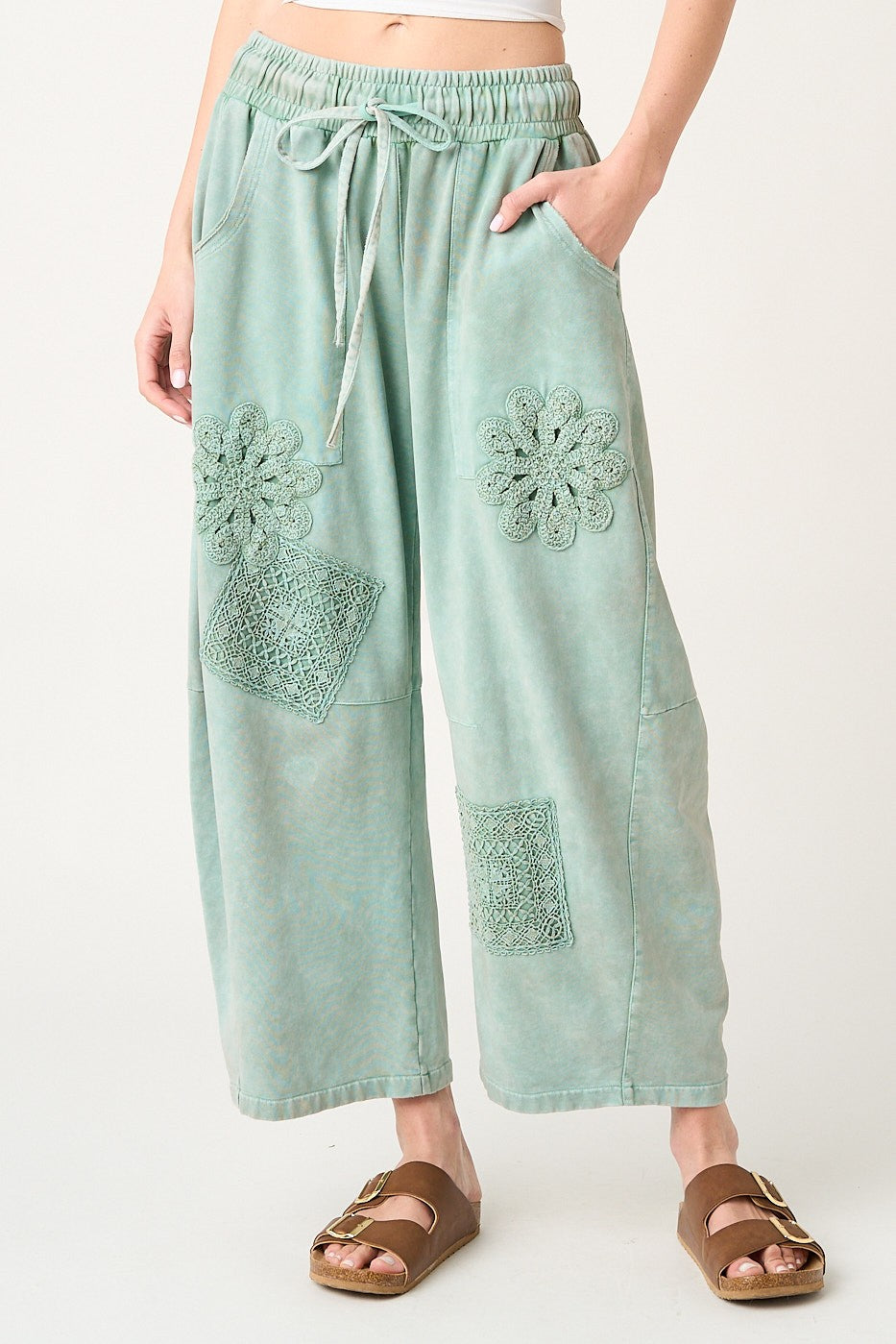 Light blue pants with floral patterns worn by a person on a white background