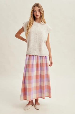 Woman wearing a white top and plaid skirt on a plain background