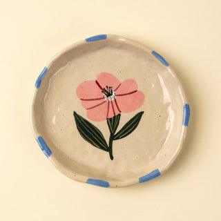 Ceramic plate with a pink flower design on a beige background