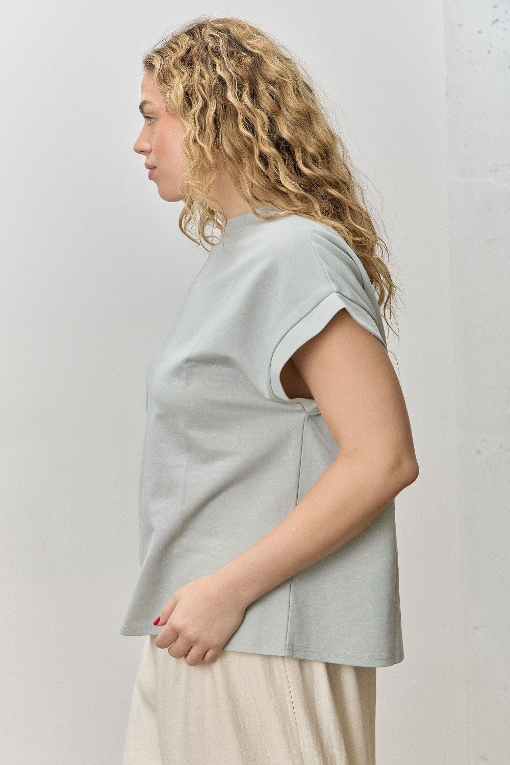 Woman wearing a light gray sleeveless top against a white background