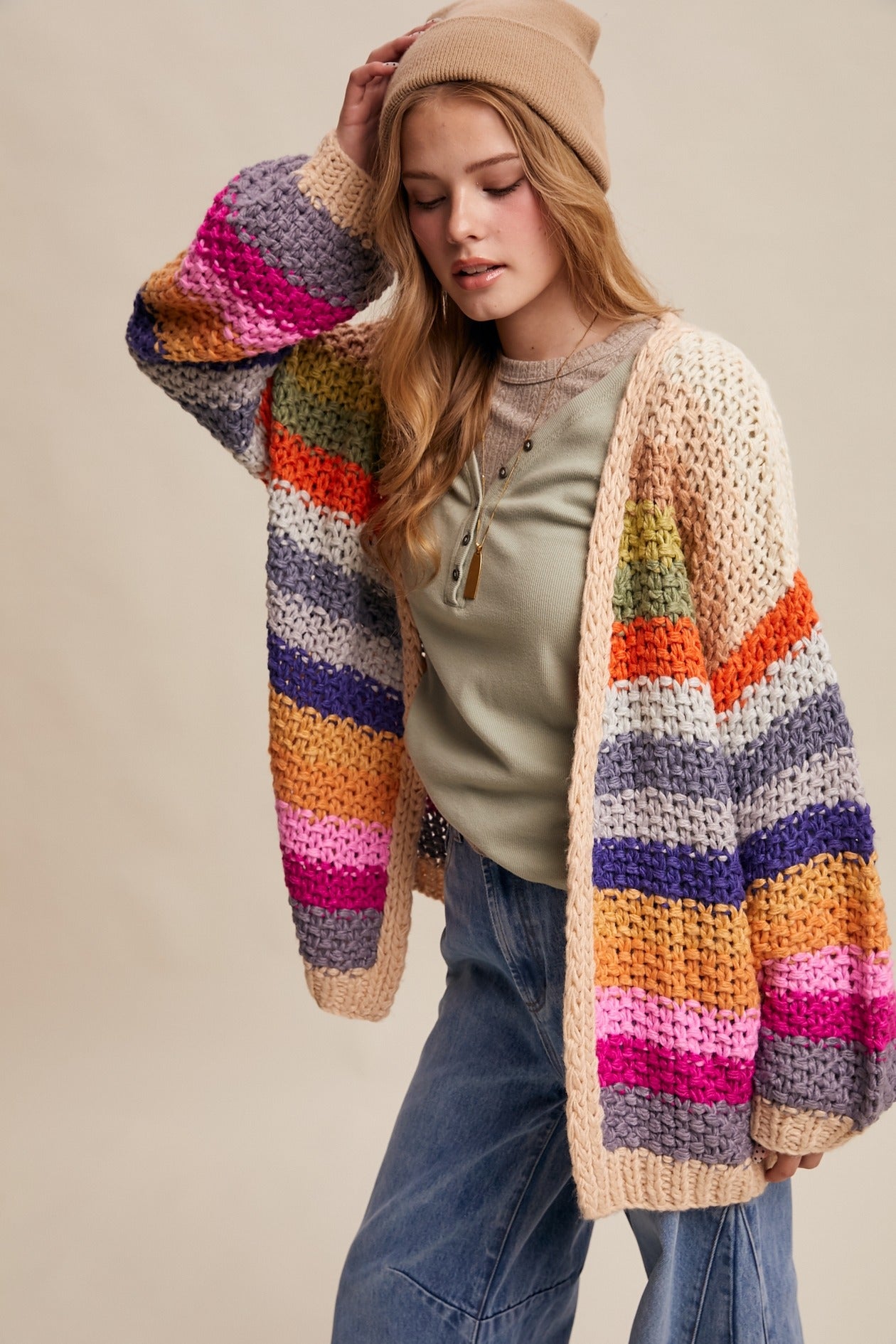 Woman wearing a colorful striped cardigan on a beige background