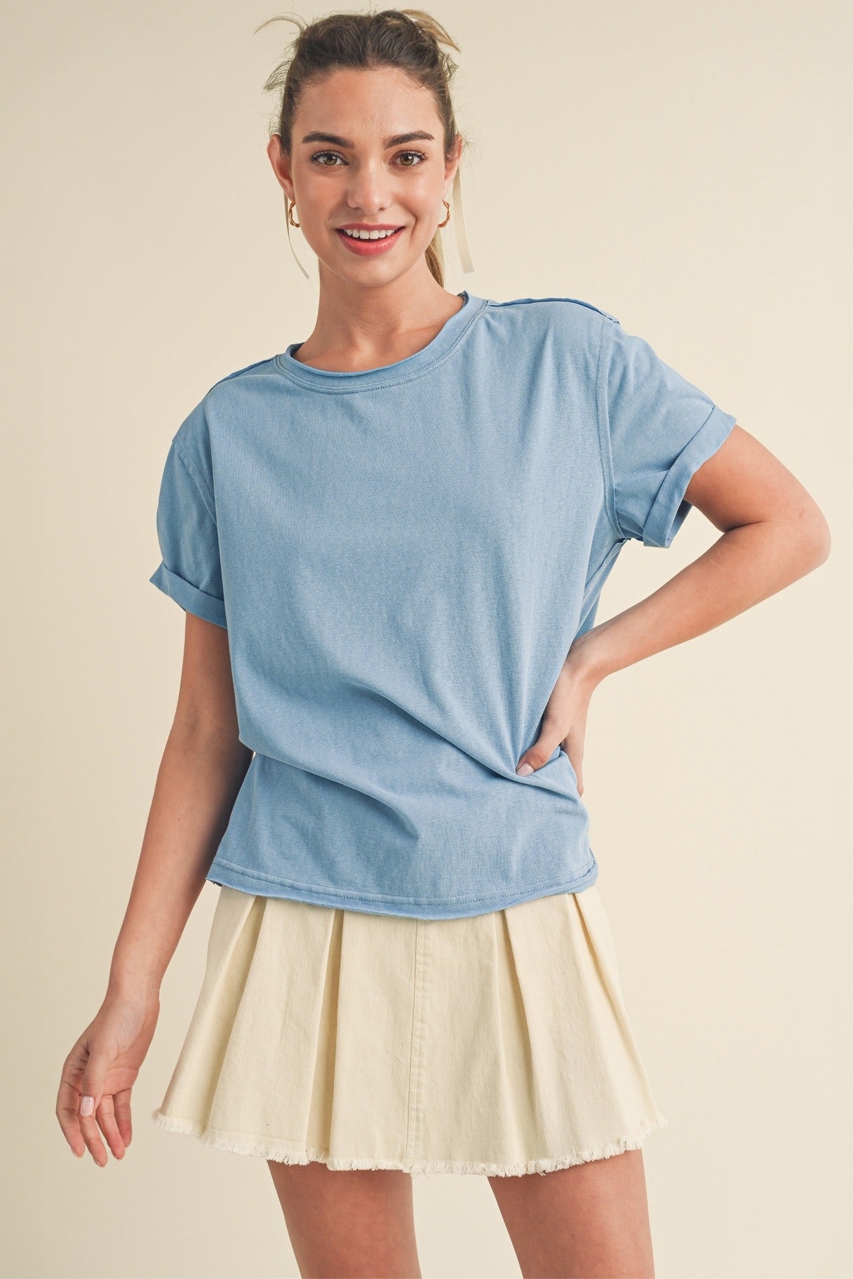 Woman wearing a blue top and beige skirt on a beige background