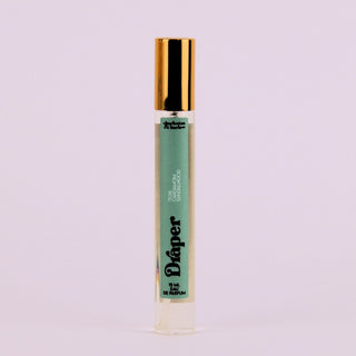 Perfume bottle with gold cap and green label on a light purple background