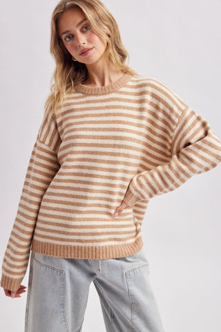 Women wearing a striped beige sweater against a neutral background.