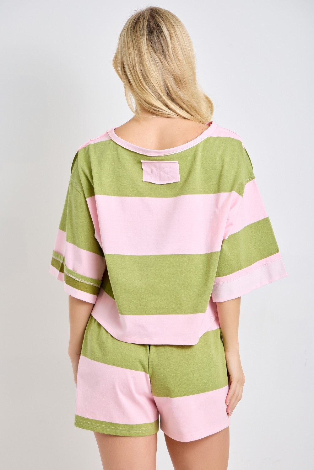 Person wearing a green and pink striped outfit on a plain background