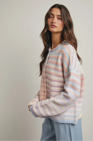 Woman wearing a pastel striped sweater against a neutral background