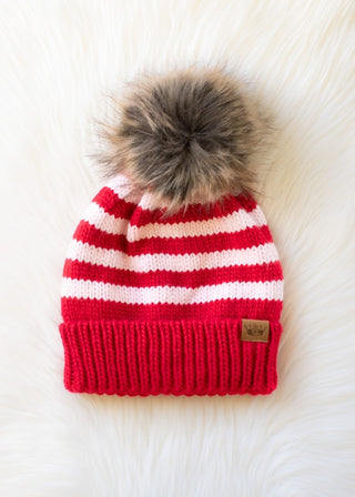 Red and white striped beanie with a fur pom-pom on a white background