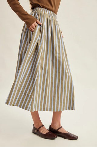 A women wearing a striped skirt against a neutral background.