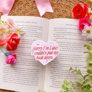 sticker that says "Sorry i'm late i couldn't put my book down" overtop of a book.