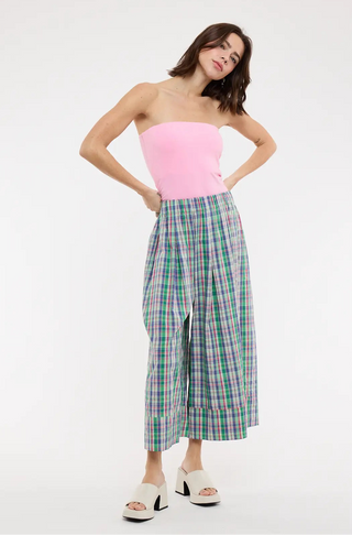 Woman wearing a pink strapless top and plaid pants on a white background