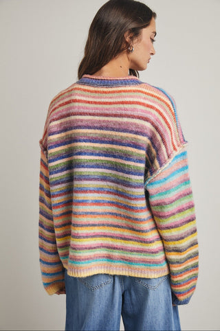 women wearing a button up cardigan with a bright rainbow stripe pattern