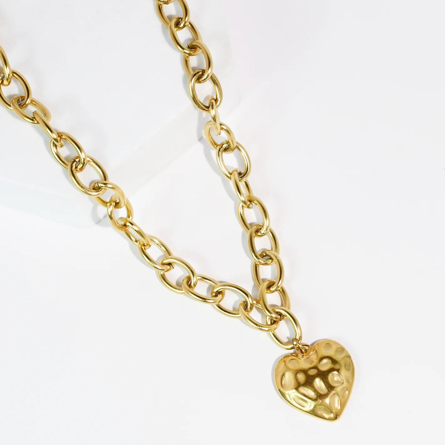 A Gold heart pendant necklace on a white background.