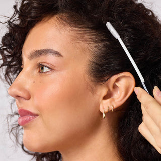 Close-up of a woman using an ear cleaning tool.
