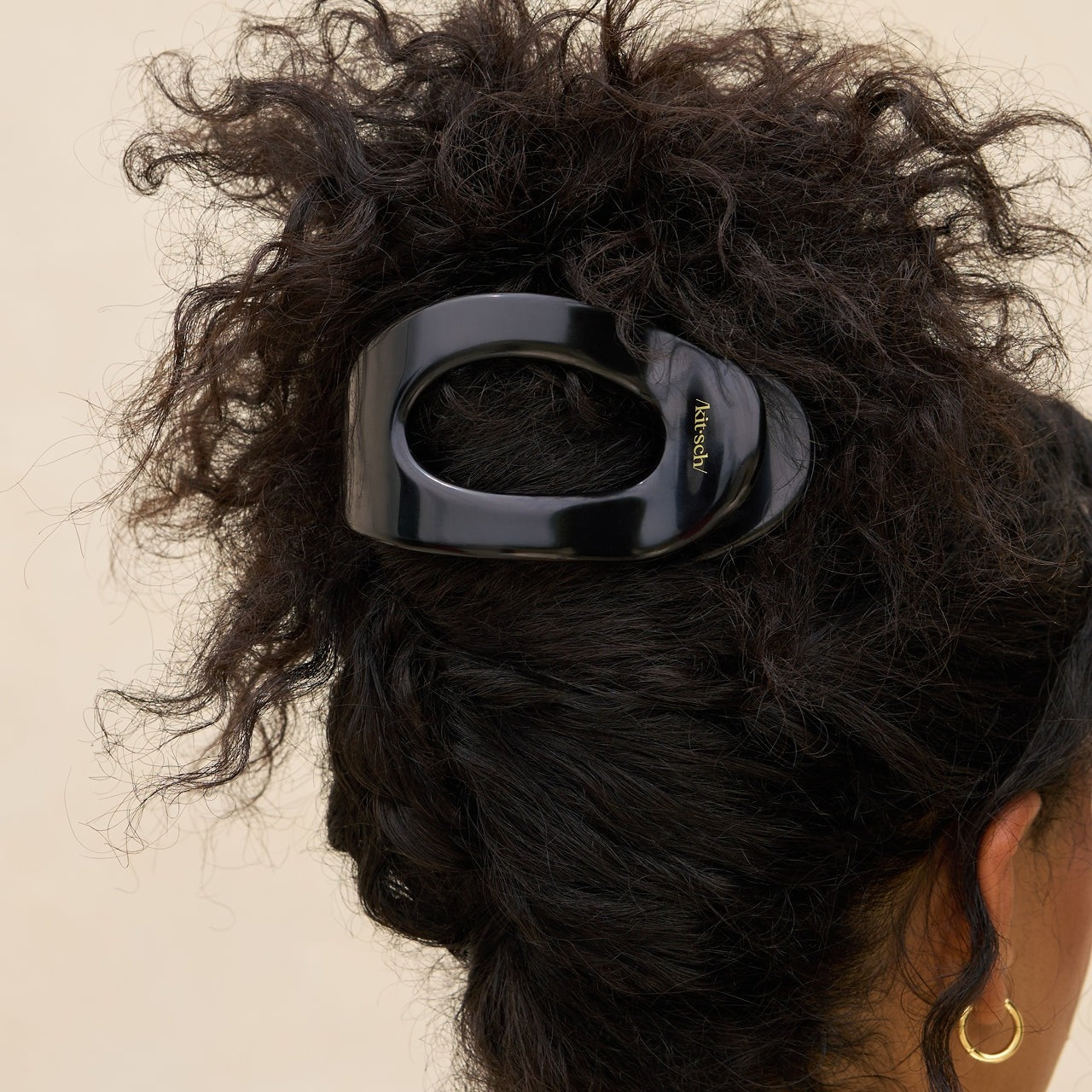 Black hair clip on a person's hair against a beige background