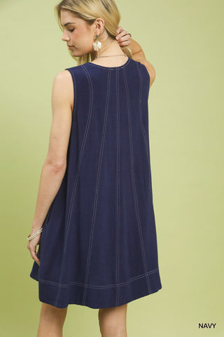 Woman wearing a navy sleeveless dress against a light green background