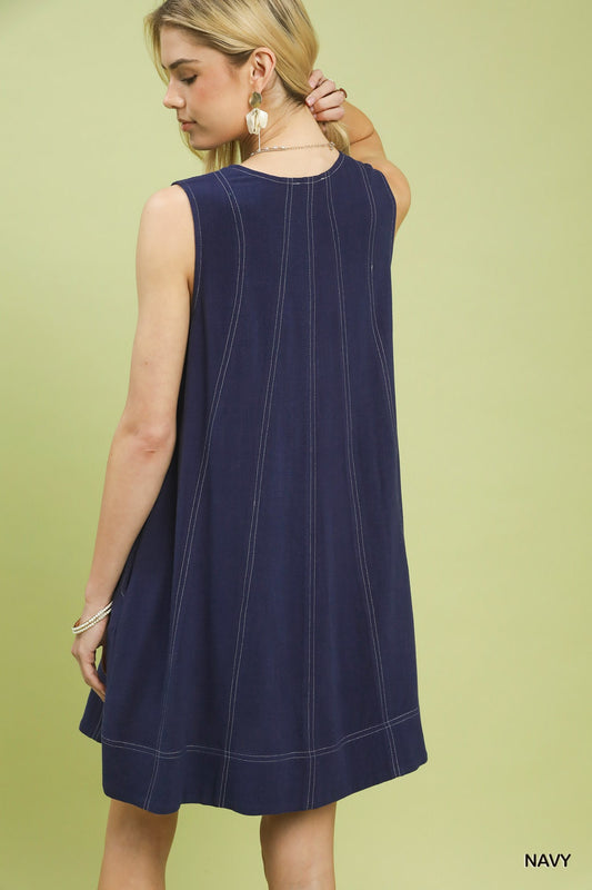 Woman wearing a navy sleeveless dress against a light green background