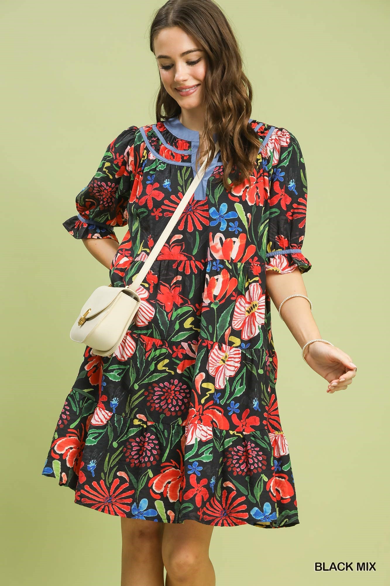 Woman wearing a colorful floral dress against a light green background
