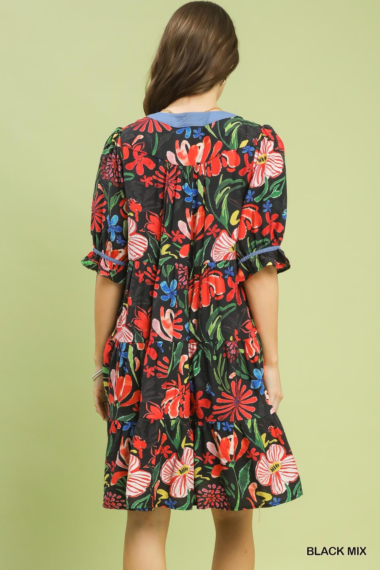 Woman wearing a colorful floral dress on a light green background