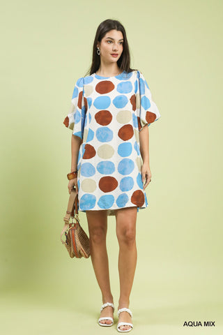 Women wearing a dotted brown and blue dress against a green background.